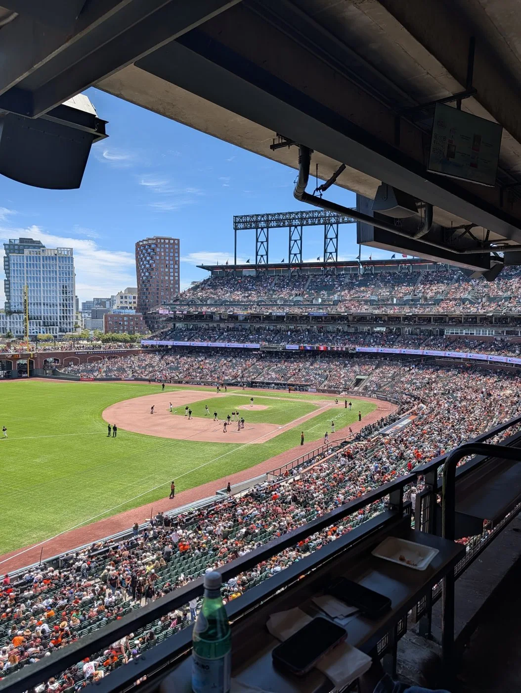 View of the Oracle Park field and packed stands from the Bonds Suite railing on a sunny day