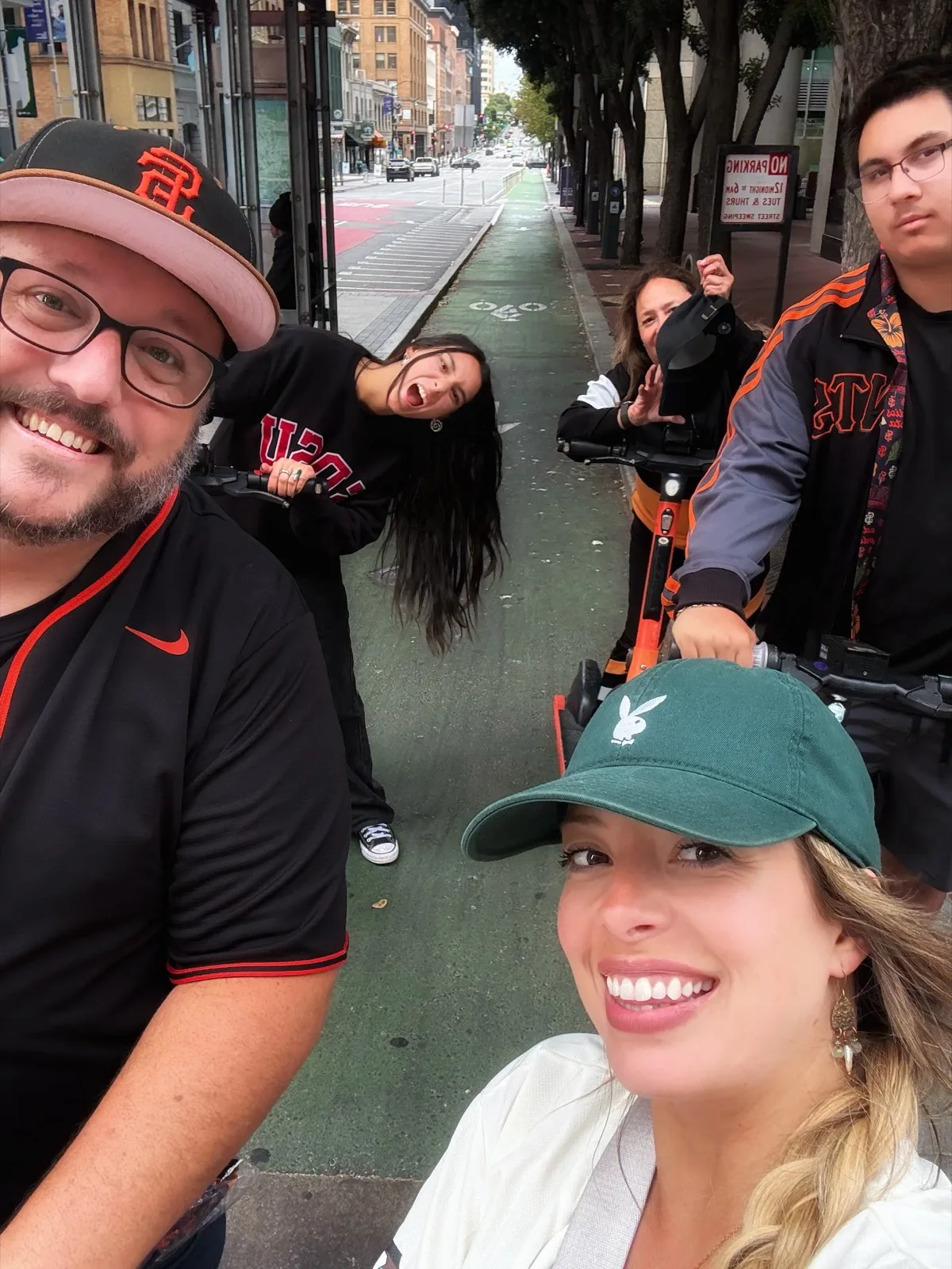 Selfie of five riders on orange e-scooters rolling up the green bike lane after the game